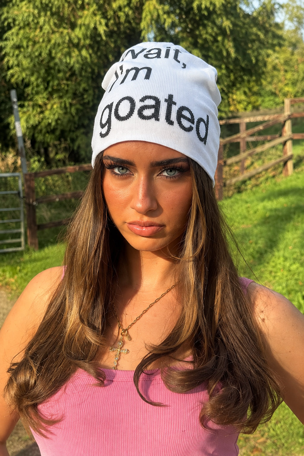 A woman wearing a white beanie with black text that reads 'wait.