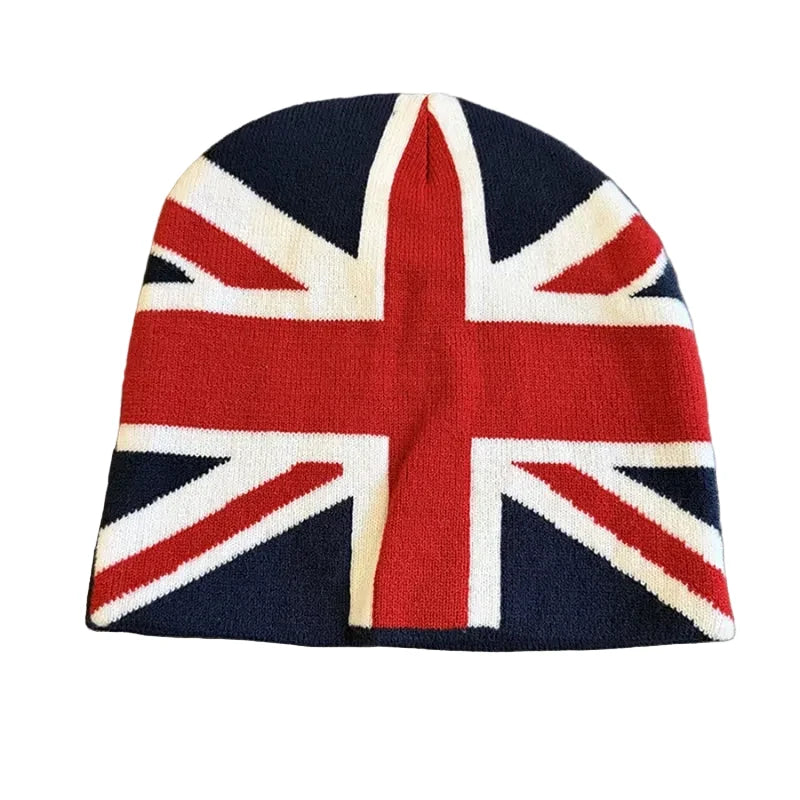 A knit beanie hat featuring the Union Jack flag pattern, laid flat on a textured gray carpet.